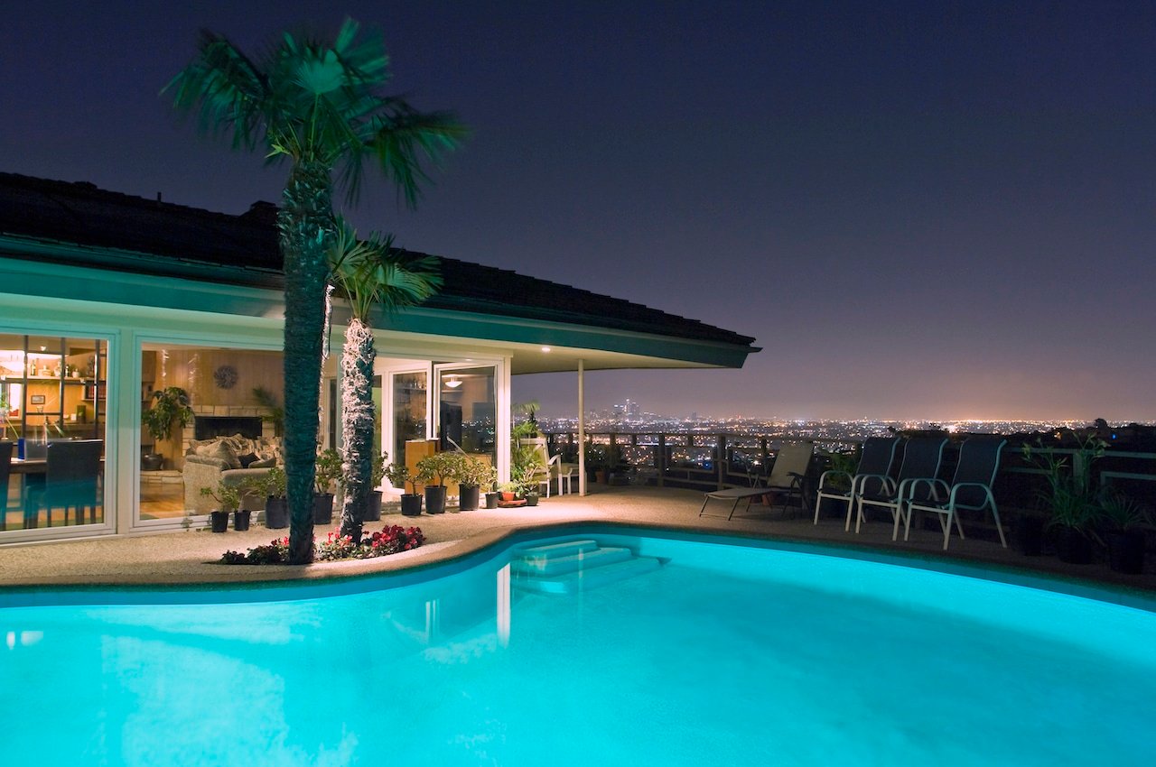 backyard pool installed by professional pool builder overlooking cityscape at night