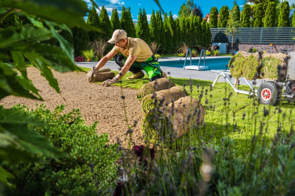 Backyard Landscaping Ideas for New Home Builds 1 man laying sod by swimming pool at new home build