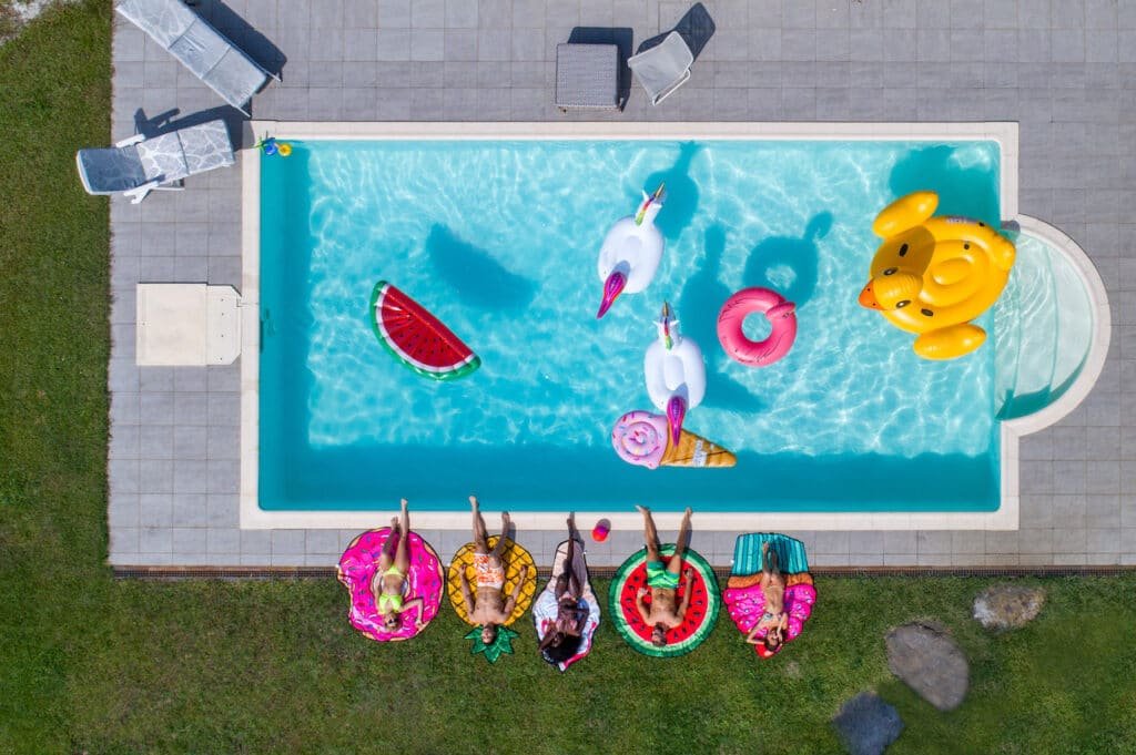 What Is a Pool Finish? 5 aerial view of friends with pool floats relaxing poolside