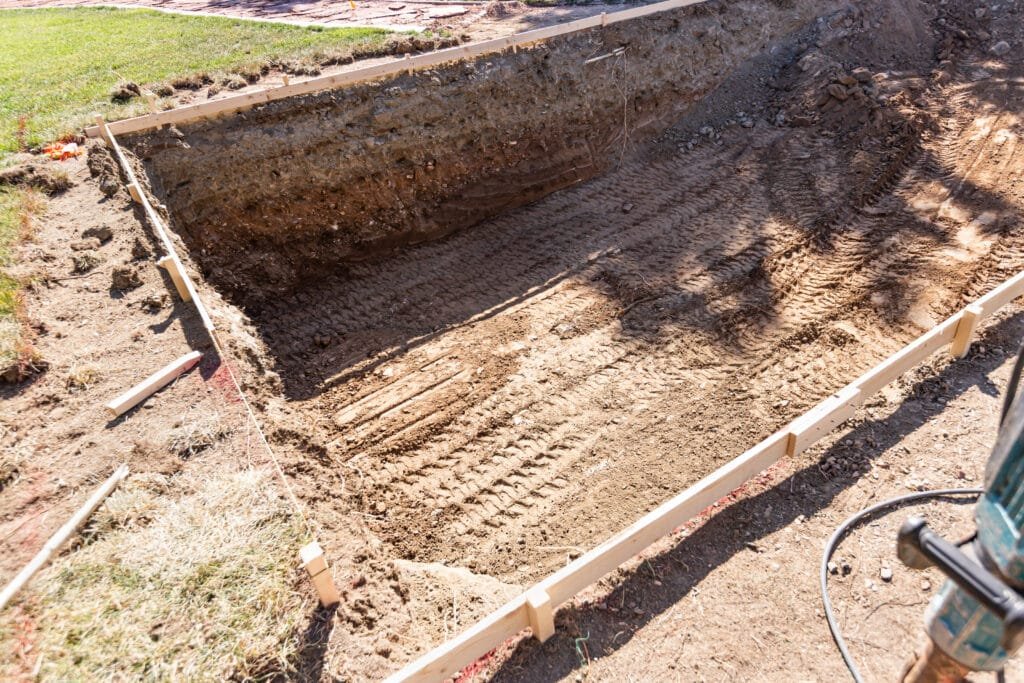 What to Expect Before, During, and After the Pool Construction Process 6 Freshly Dug Hole In Yard Preparing For Swimming Pool Installation